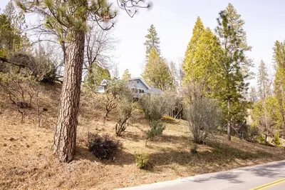 a house on the side of a hill with trees at Near Yosemite Bass Lake Cabin with Hot Tub, Lake View, Pet Friendly in Bass Lake