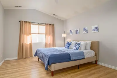 a bedroom with a bed with a blue comforter and a window at Designer Home conveniently located in Reno NV in Reno