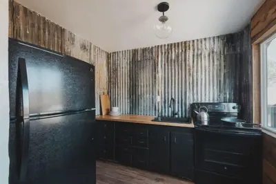a kitchen with a black refrigerator and a sink at Secluded rustic 2-bedroom cabin on private land in Miramonte