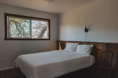 a bedroom with a white bed with a window at Secluded rustic 2-bedroom cabin on private land in Miramonte