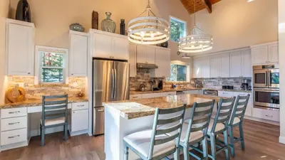 a kitchen with white cabinets and a large island with chairs at Views Mins to Skiing Lake Incline Village Incline Serenity by AvantStay in Incline Village