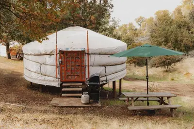 a yurt with a picnic table and an umbrella at Glamping yurt at nature retreat in Sequoia NForest in Miramonte