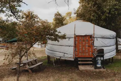 a yurt with a wooden door and a bench at Glamping yurt at Sequoia Highland Camp in Miramonte