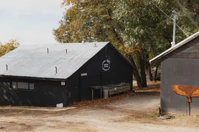 a black barn with a metal roof next to a building at Glamping yurt at Sequoia Highland Camp in Miramonte