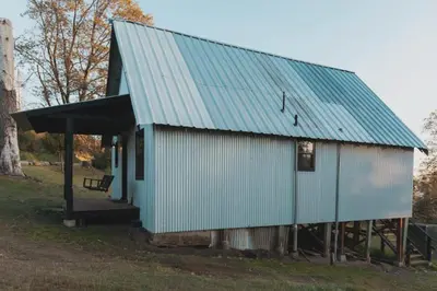 a blue building with a blue roof on a field at Secluded rustic 3-bedroom cabin on private land in Miramonte