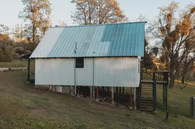 a large white barn with a blue roof at Secluded rustic 3-bedroom cabin on private land in Miramonte