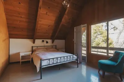 a bedroom with a bed and a chair and a window at Spacious 4-bedroom cabin on secluded private land in Miramonte