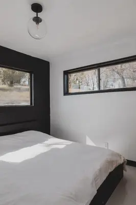 a bedroom with a white bed and two windows at Secluded rustic 2-bedroom cabin at nature retreat in Miramonte