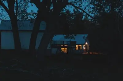a house lit up at night with lights in front at Secluded rustic 2-bedroom cabin at nature retreat in Miramonte