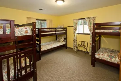 a room with three bunk beds and a chair at Moderne Hostel in Mammoth Lakes