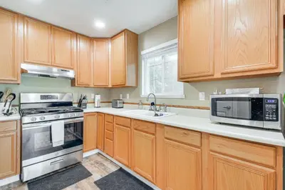 a kitchen with wooden cabinets and stainless steel appliances at Coulterville Home with Gazebo Near Lakes and Hiking! in Coulterville