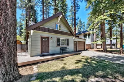 a small white house with a porch and a tree at CYH0876 - Island Cabin cabin in South Lake Tahoe