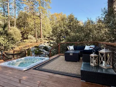 a patio with a jacuzzi tub on a deck at Elegant Blackwood Grove by Casa Oso in Mariposa