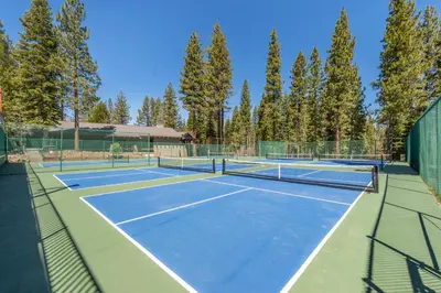 two tennis courts with trees in the background at Luxury Home Walk to Ski Lifts 6 Pools Food Private Hot-Tub Yard Fun Bunk Room in Truckee