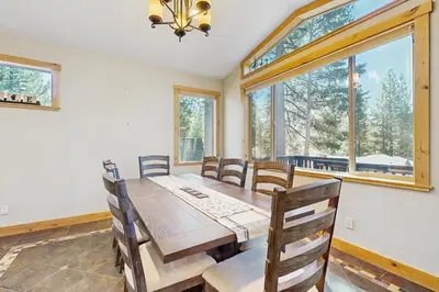 a dining room with a table and chairs and windows at The Tahoe Timber House in South Lake Tahoe
