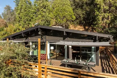 a house with a black roof and a wooden fence at Modern 2 Bedrm Kids, Dog, Hot Tb, Game Room, 9 min Bass Lake in Oakhurst