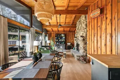 a dining room with wooden walls and a stone fireplace at Modern 2 Bedrm Kids, Dog, Hot Tb, Game Room, 9 min Bass Lake in Oakhurst