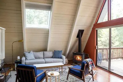 a living room with a couch and a wood stove at Stunning A-Frame Cabin Rental for Four Guests in Arnold, California in Arnold