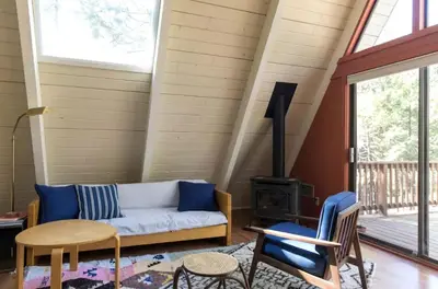 a living room with a couch and a wood stove at Stunning A-Frame Cabin Rental for Four Guests in Arnold, California in Arnold