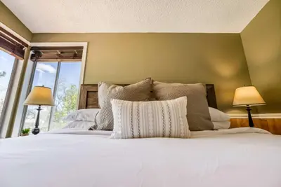 a bedroom with a white bed with two lamps at Cozy 3BR Family Home with Patio & BBQ grill Close to Casinos and Shops in Reno