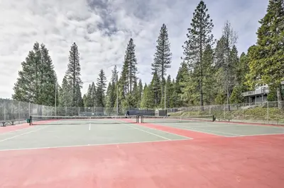 a tennis court with trees in the background at Game Room Blue Lake Mountain Retreat in Arnold in Arnold