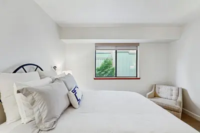 a white bedroom with a bed and a chair at Modern Mountain Escape in South Lake Tahoe