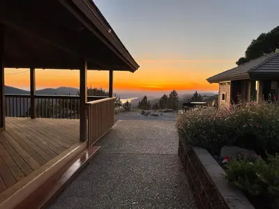 a house with a deck with a sunset in the background at Priest Ranch with Guest House and Pool in Big Oak Flat
