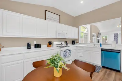 a kitchen with white cabinets and a wooden table at University Pastoral - Family Perfect Close to UCM in Merced