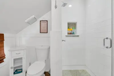 a white bathroom with a toilet and a shower at CC Cabin - Full Game Room & Wrap Around Deck in Shaver Lake