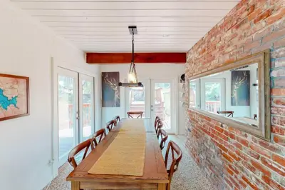 a dining room with a brick wall and a wooden table at CC Cabin - Full Game Room & Wrap Around Deck in Shaver Lake