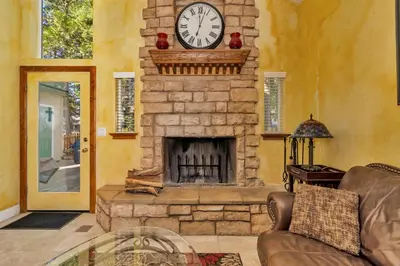 a living room with a stone fireplace with a clock at A Tuscan Adventure in California 3 BDR Sleeps 8 in Shaver Lake