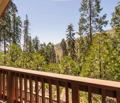 a balcony with a view of the woods at Cavu Cabin - A Classic Mountainside Escape in Shaver Lake