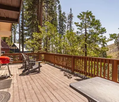 a wooden deck with a picnic table and chairs on it at Cavu Cabin - A Classic Mountainside Escape in Shaver Lake
