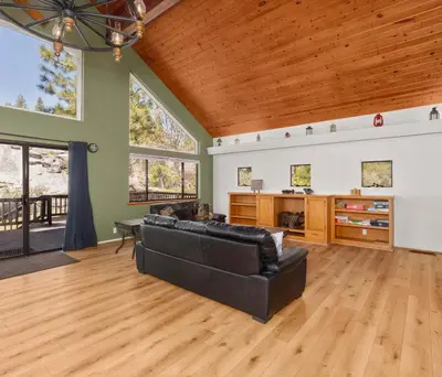 a living room with a black couch and wooden ceilings at Granite View Lodge - Minutes from Water in Shaver Lake