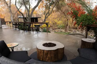 a patio with a tree stump coffee table and a tree stump at River Magic - Riverfront Family Fun & Lux Design in Three Rivers