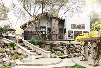 a house with a stone staircase in a garden at River Magic - Riverfront Family Fun & Lux Design in Three Rivers