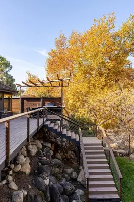 a wooden bridge over a river with rocks at River Soul – Riverfront Luxury & Stunning Views in Three Rivers