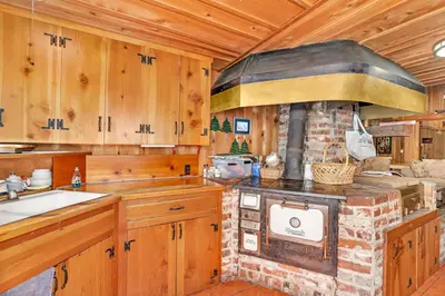 a kitchen with a stone stove and wooden cabinets at Rustic Knotty Pine - Old Cabin Vibes in Shaver Lake