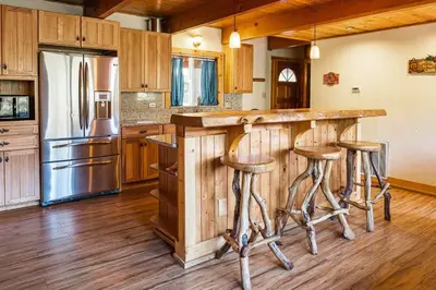 a kitchen with a bar with stools and a refrigerator at Red House - Minutes to Shaver Lake in Shaver Lake