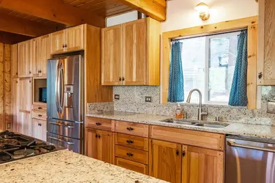 a kitchen with wooden cabinets and a stainless steel refrigerator at Red House - Minutes to Shaver Lake in Shaver Lake