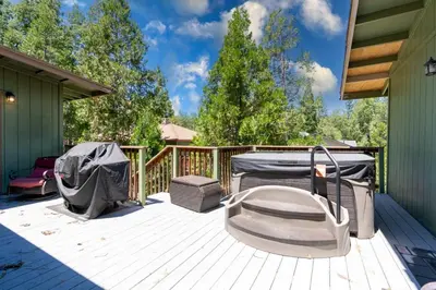 a deck with a bed and a grill on it at Immersed in Nature Manzanita Cabin with Hot Tub in Oakhurst