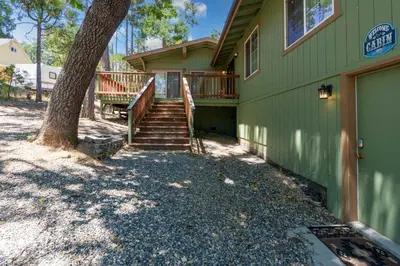 a green house with stairs and a tree at Immersed in Nature Manzanita Cabin with Hot Tub in Oakhurst