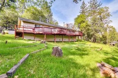 a house with a porch on a green field at Sierra Serenity Scenic Mtn Escape with Game Room in Oakhurst