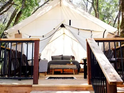 a tent with a bed and a table on a deck at Safari Tents for Romantic Escapes in California's El Dorado County in Pilot Hill
