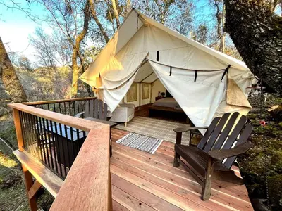 a tent with a hammock and a chair on a deck at Safari Tents for Romantic Escapes in California's El Dorado County in Pilot Hill
