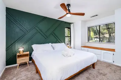 a bedroom with a large white bed with a green wall at Spacious Mountain View Home - Pool, Spa & Game Rm in Oakhurst