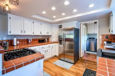 a kitchen with white cabinets and a stainless steel refrigerator at Spacious Mountain View Home - Pool, Spa & Game Rm in Oakhurst