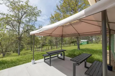 a patio with two benches and an umbrella at Green Meadows at Sky Ranch, 13 miles from Yosemite in Oakhurst