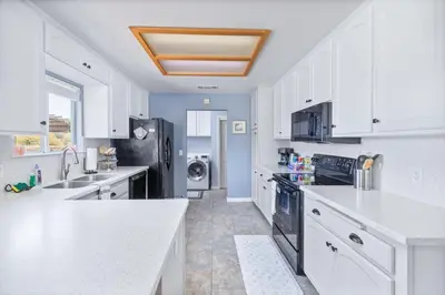 a kitchen with white cabinets and a black refrigerator at Sunset Lookout Mountain villa, Meadows, Gazebo in Coarsegold