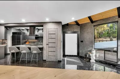 a kitchen with a large window and a kitchen with stools at Modern Mountain Luxury Soak, Stay, & Be Spoiled in Shaver Lake